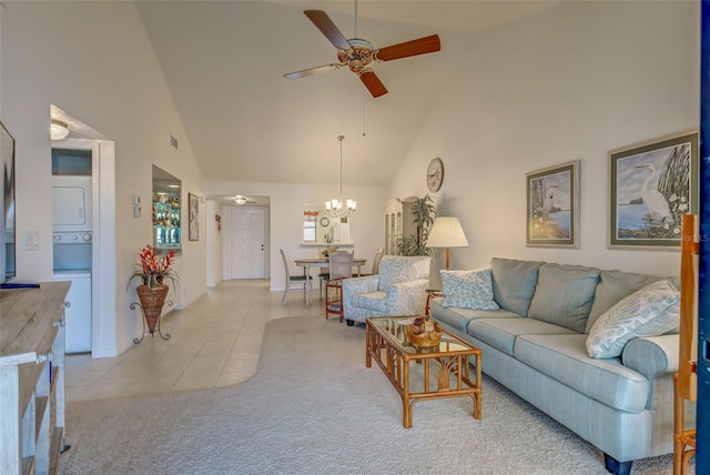 tiled living room featuring high vaulted ceiling and ceiling fan with notable chandelier