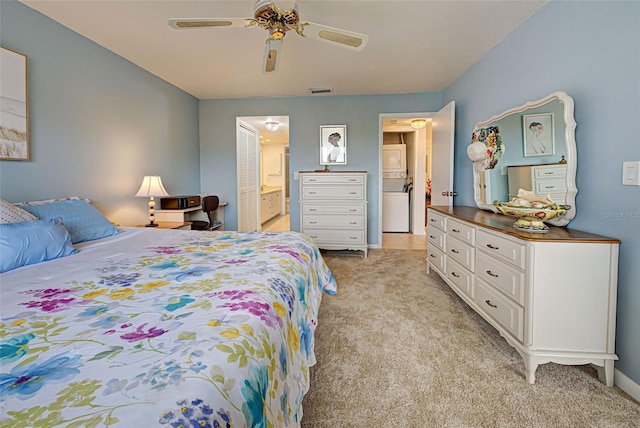 carpeted bedroom featuring stacked washer and clothes dryer, ceiling fan, and ensuite bath