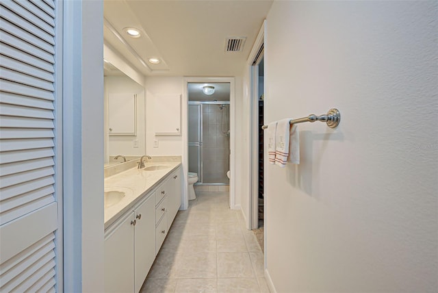 bathroom with toilet, vanity, tile patterned floors, and a shower with shower door