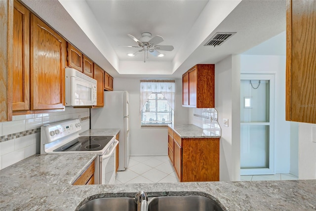 kitchen with tasteful backsplash, light tile patterned floors, ceiling fan, a raised ceiling, and white appliances