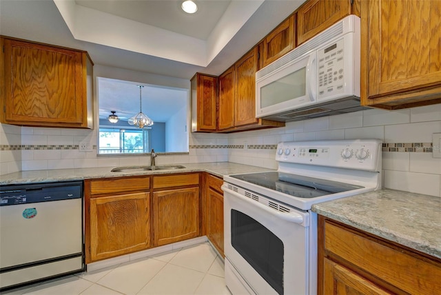 kitchen featuring sink, white appliances, hanging light fixtures, light tile patterned flooring, and decorative backsplash