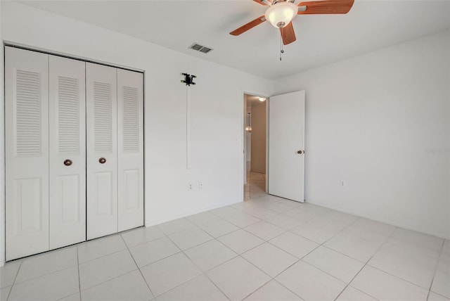 unfurnished bedroom with light tile patterned floors, ceiling fan, and a closet