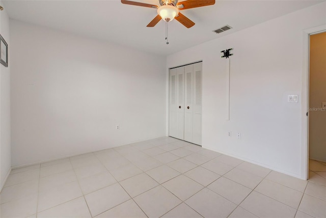 unfurnished bedroom with light tile patterned floors, a closet, and ceiling fan