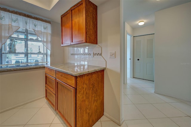 kitchen with light tile patterned floors, decorative backsplash, and light stone countertops