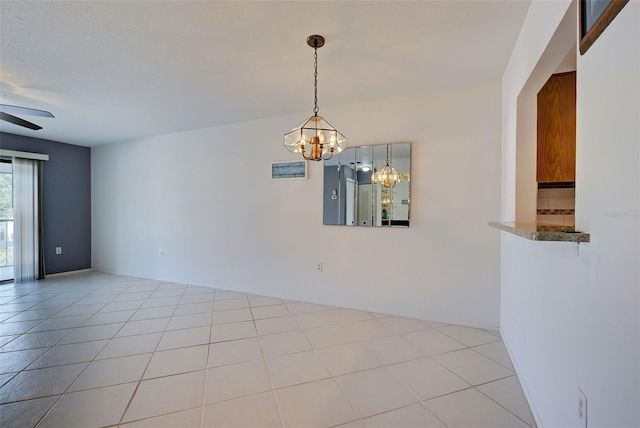 empty room featuring light tile patterned floors and ceiling fan with notable chandelier