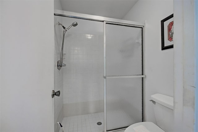 bathroom featuring toilet and a shower with shower door