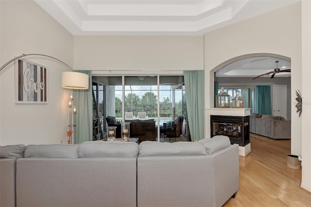 living room with ceiling fan, hardwood / wood-style flooring, and a tray ceiling