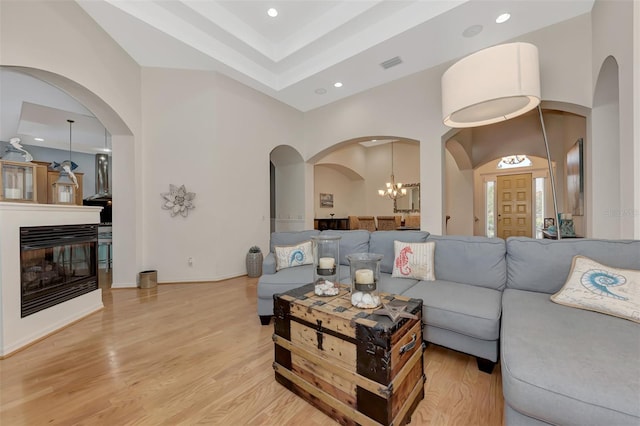 living room with light hardwood / wood-style floors, a chandelier, and a towering ceiling