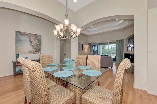 dining room featuring light hardwood / wood-style flooring, a chandelier, and a tray ceiling