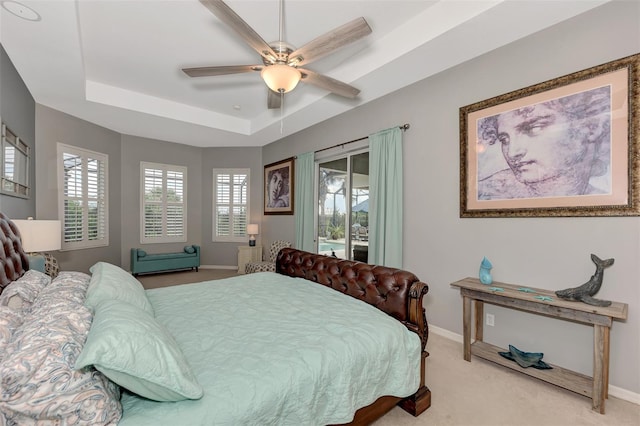 bedroom featuring access to outside, multiple windows, a raised ceiling, and ceiling fan