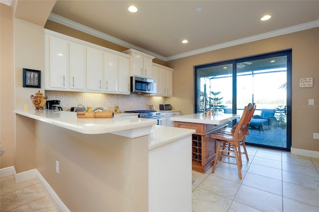 kitchen with a center island, white cabinetry, stainless steel appliances, decorative backsplash, and a breakfast bar area