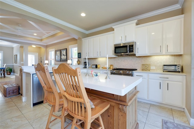 kitchen with decorative backsplash, a center island with sink, crown molding, white cabinets, and appliances with stainless steel finishes