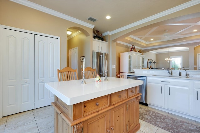 kitchen featuring appliances with stainless steel finishes, sink, a center island, coffered ceiling, and crown molding