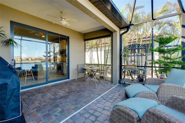 sunroom featuring a healthy amount of sunlight, a water view, and ceiling fan