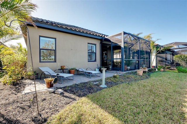 back of house with a yard, a patio, and glass enclosure