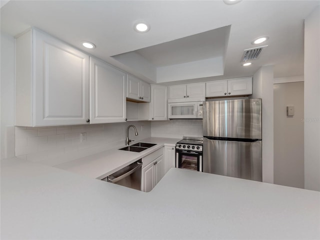 kitchen with white cabinets, decorative backsplash, stainless steel appliances, and sink