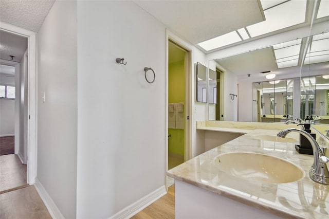 bathroom featuring a skylight, vanity, wood-type flooring, and a textured ceiling