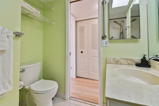 bathroom with tile patterned floors, a skylight, vanity, and toilet