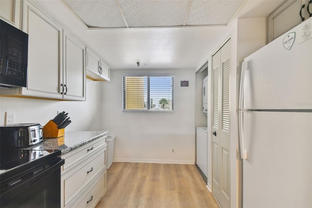 kitchen featuring white cabinets, light wood-type flooring, light stone countertops, and black appliances