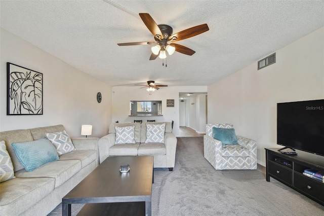 living room featuring ceiling fan, carpet, and a textured ceiling