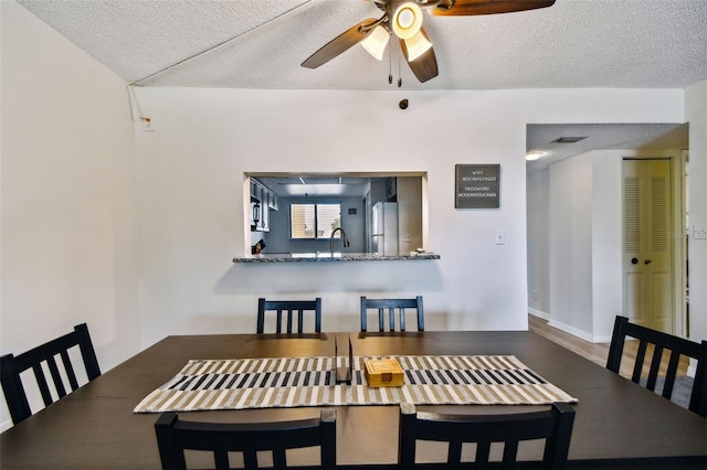 dining room featuring ceiling fan, sink, and a textured ceiling