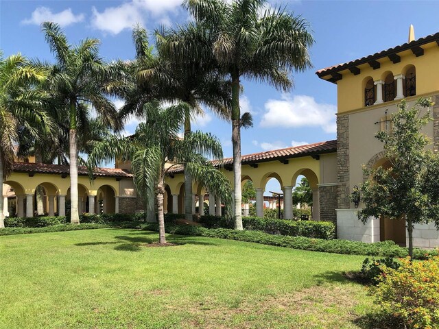 20190 Ragazza Cir Unit 202, Venice, FL 34293 - mediterranean / spanish house featuring stucco siding, a tiled roof, a front yard, and stone siding