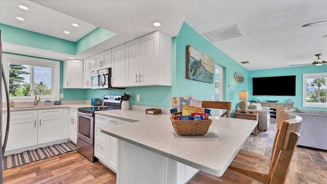 kitchen with a breakfast bar, stainless steel appliances, light hardwood / wood-style flooring, white cabinetry, and plenty of natural light