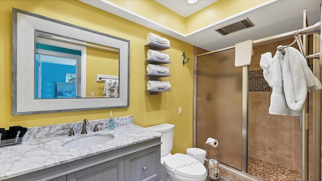 bathroom featuring a shower with door, vanity, and toilet