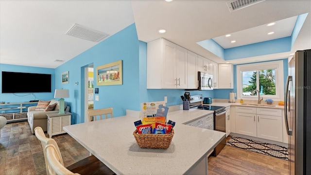 kitchen with kitchen peninsula, appliances with stainless steel finishes, white cabinets, and sink