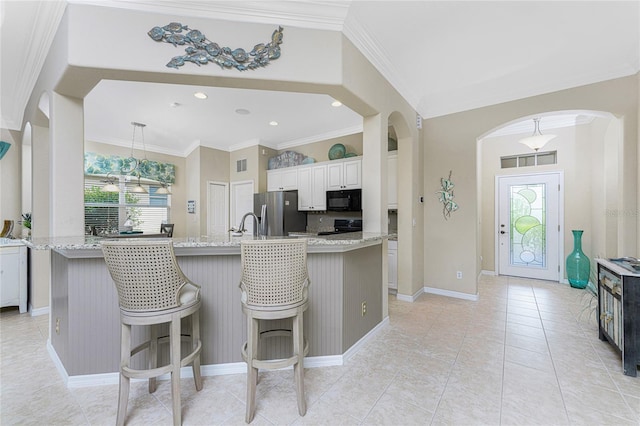 kitchen featuring white cabinetry, pendant lighting, a center island with sink, black appliances, and ornamental molding