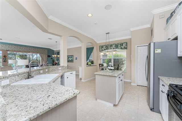 kitchen featuring light stone counters, sink, decorative light fixtures, a center island, and white cabinetry