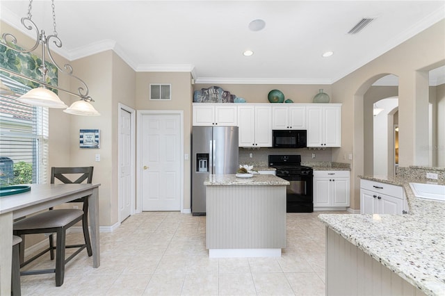 kitchen with pendant lighting, light stone counters, ornamental molding, and black appliances