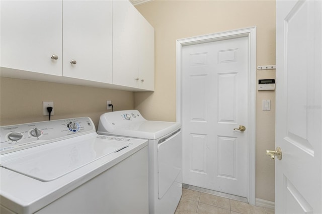 laundry area with washing machine and clothes dryer, light tile patterned flooring, and cabinets