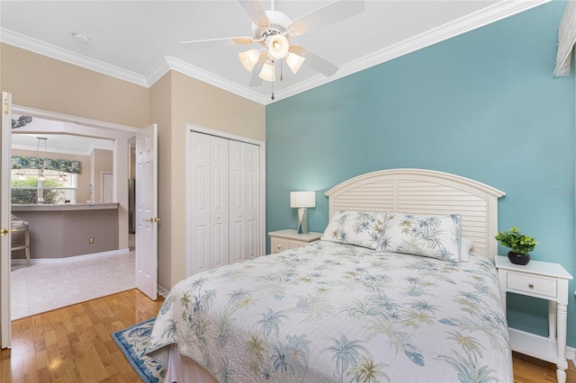 bedroom featuring a closet, ceiling fan, light hardwood / wood-style flooring, and crown molding