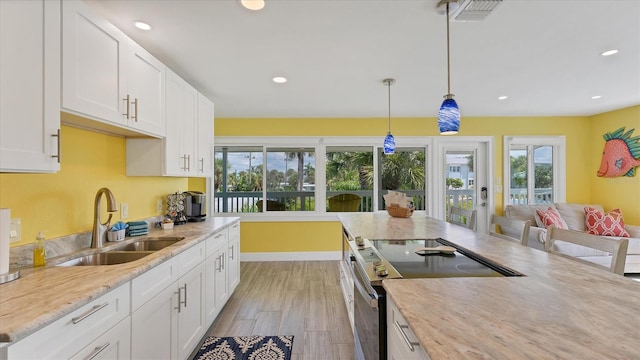 kitchen featuring light wood-type flooring, white cabinetry, hanging light fixtures, and stainless steel range with electric cooktop