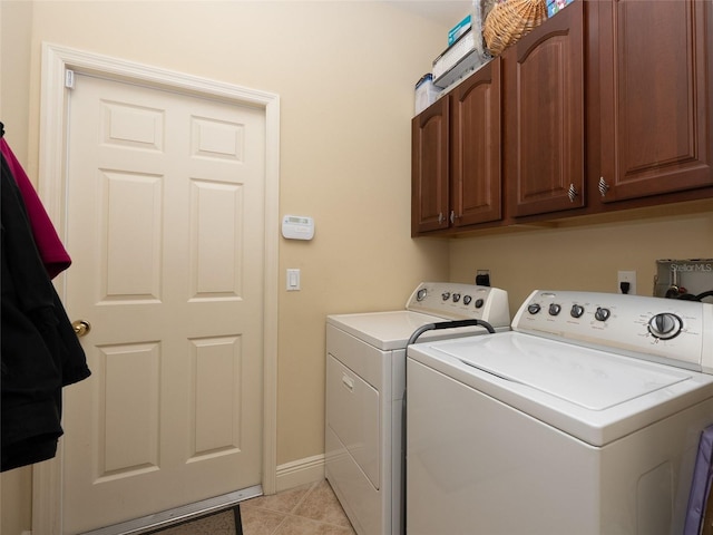 laundry area featuring washer and clothes dryer, cabinets, and light tile patterned floors