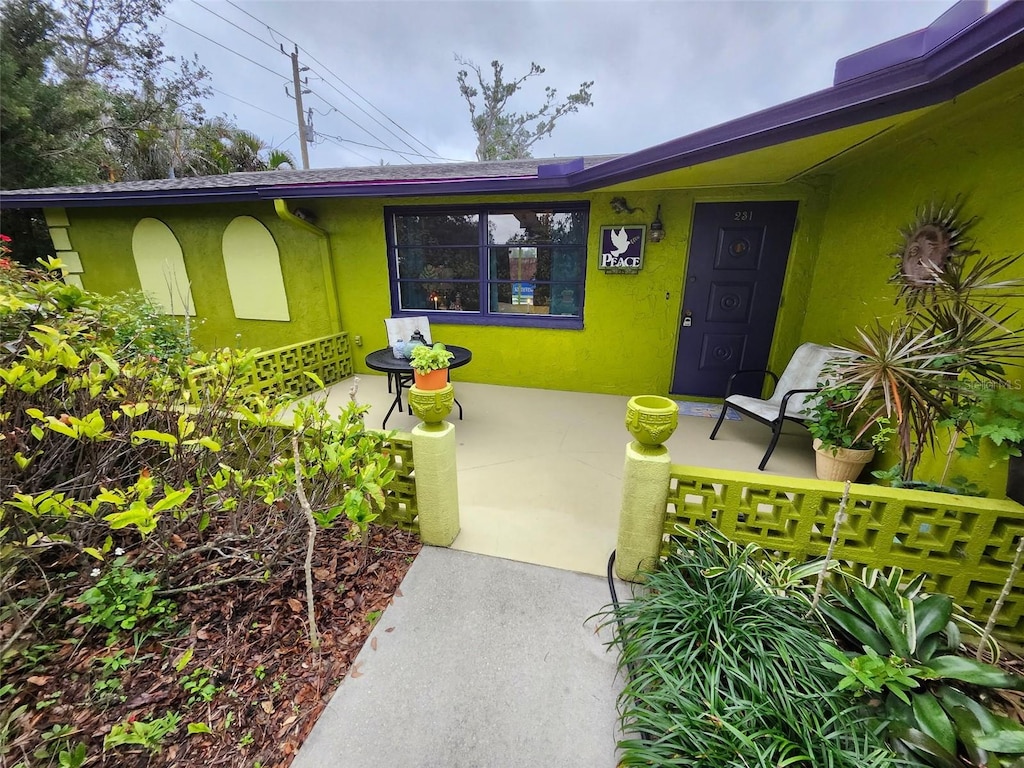 property entrance with covered porch and stucco siding