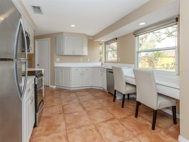 kitchen featuring white cabinetry, sink, light tile patterned floors, and stainless steel appliances