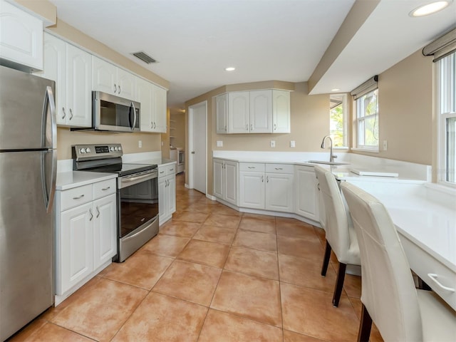 kitchen featuring light tile patterned floors, white cabinetry, sink, and appliances with stainless steel finishes