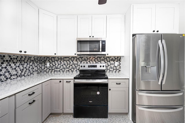 kitchen featuring stainless steel appliances, light stone countertops, white cabinetry, and tasteful backsplash