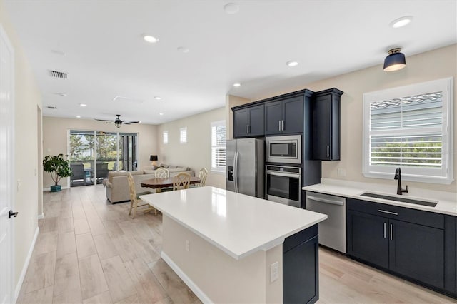 kitchen featuring a kitchen island, appliances with stainless steel finishes, ceiling fan, and sink