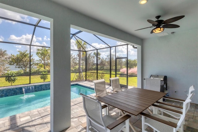 view of pool with ceiling fan, a patio area, glass enclosure, and pool water feature