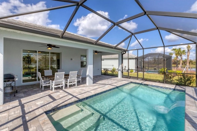 view of pool featuring grilling area, a patio, ceiling fan, and glass enclosure