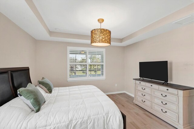 bedroom featuring a tray ceiling and light hardwood / wood-style flooring