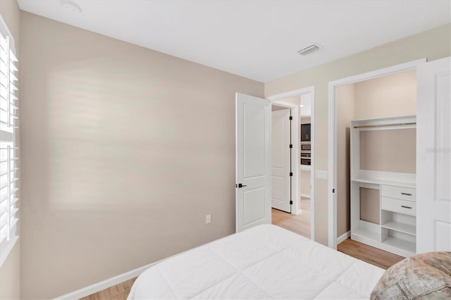 bedroom with a closet, multiple windows, and light wood-type flooring