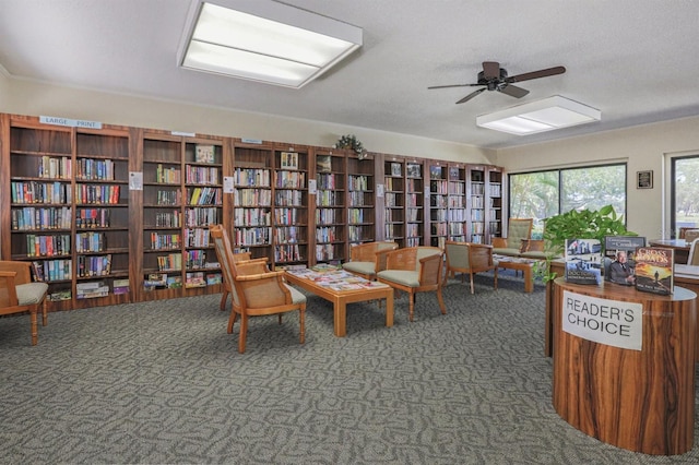 living area featuring ceiling fan, a textured ceiling, and dark colored carpet