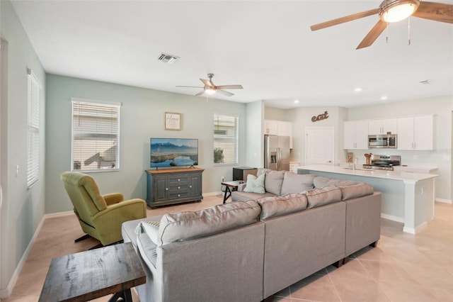 tiled living room featuring ceiling fan and sink