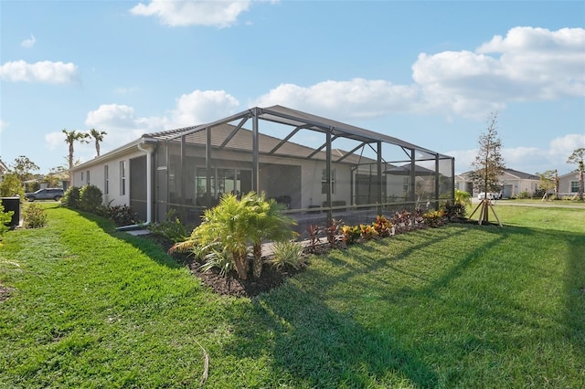 rear view of property with glass enclosure and a yard