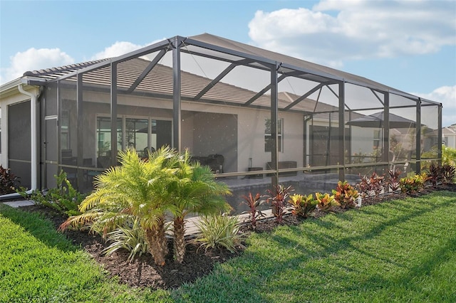 rear view of house featuring a yard and glass enclosure