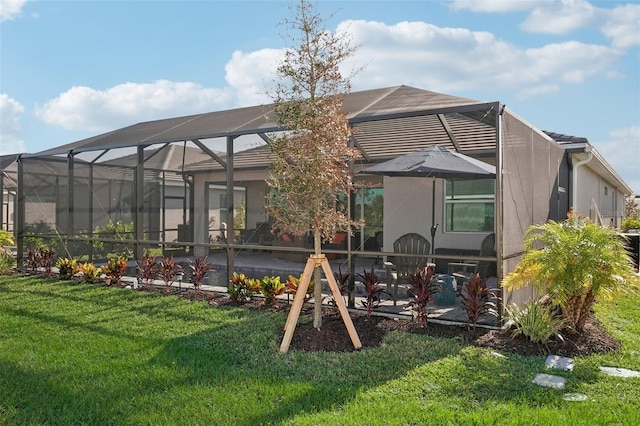 rear view of property with a lawn, glass enclosure, and a patio